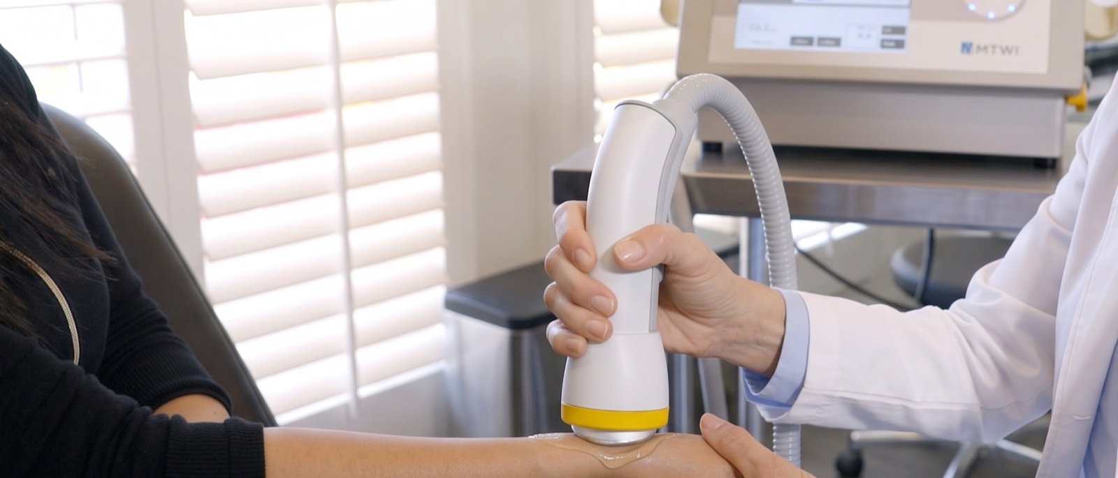 Shock wave therapy applicator being used on a patient's elbow